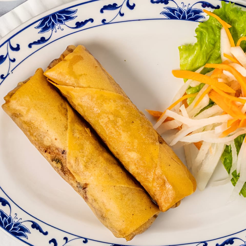 Two crispy Bambu Vietnamese egg rolls with a side of fresh lettuce, shredded carrots, and daikon.